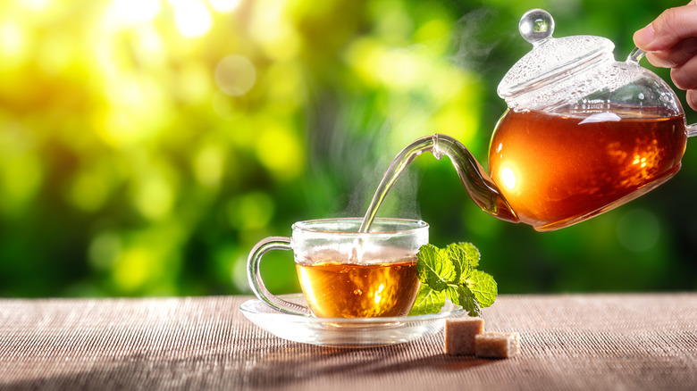 Pouring black tea in cup