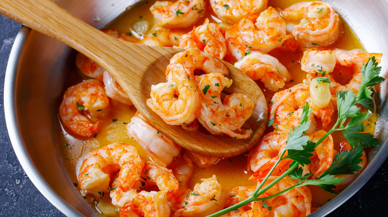 shrimp scampi in pan with wooden spoon