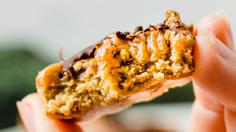 Hand holding caramel chocolate cookie bar