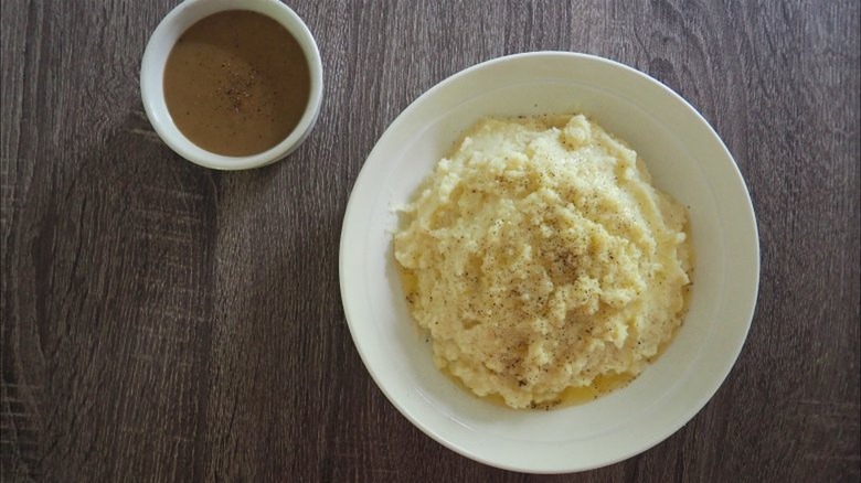 Bowl of mashed potatoes next to bowl of brown gravy