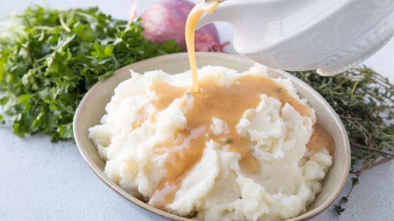 Light brown gravy being poured over mashed potatoes