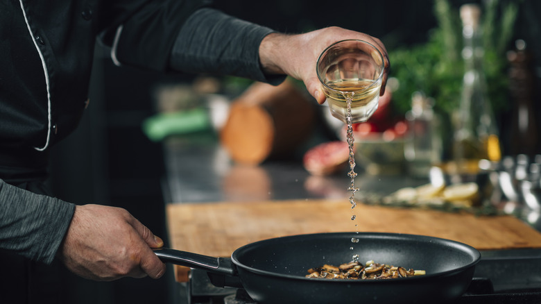 Pouring white wine into pan