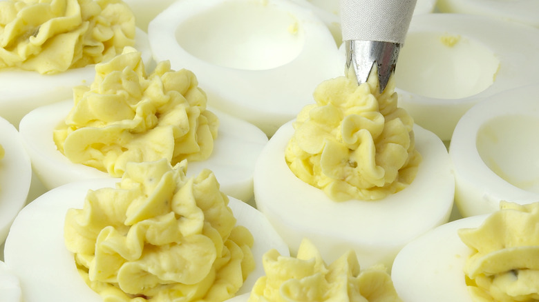 piping filling into deviled eggs