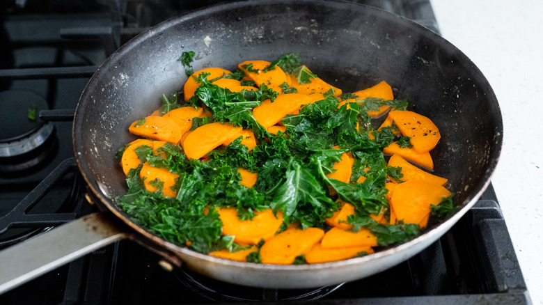 sweet potatoes and kale cooking in a pan