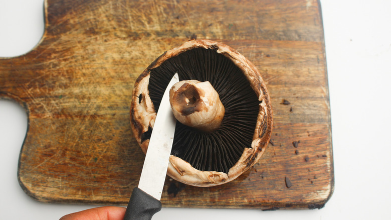 Slicing the stem off the mushroom 