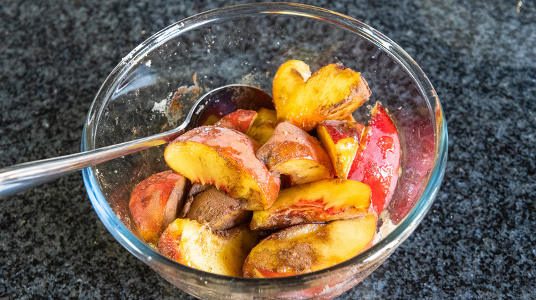 sliced peaches in bowl with sugar and cinnamon