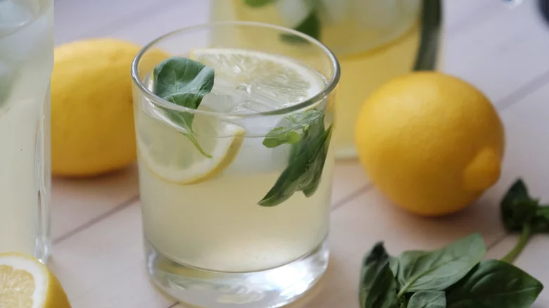Short glass of lemonade with basil leaves on top