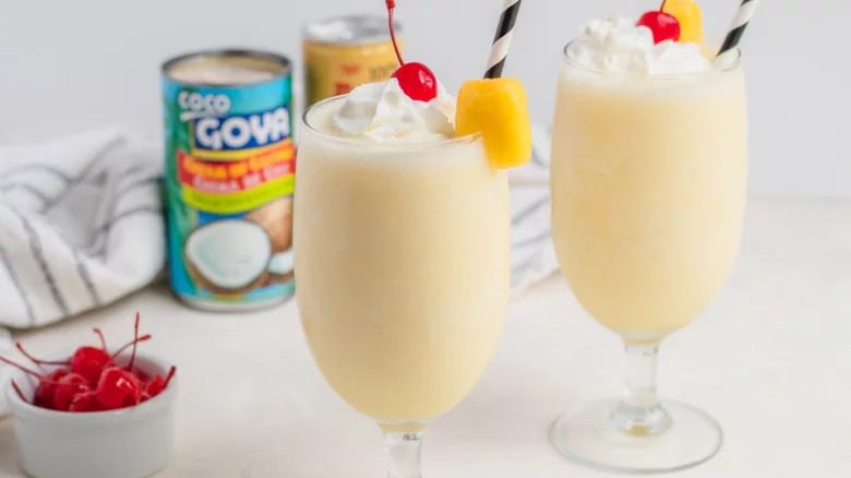 Two pina coladas with pineapple and cherry garnishes