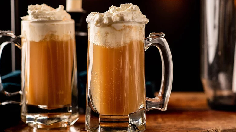 Two pints of golden butterbeer with whipped cream on top