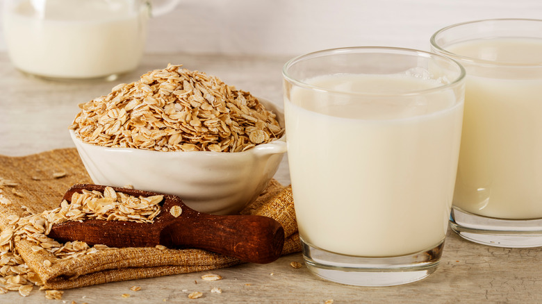 glases of oat milk next to bowl of oats