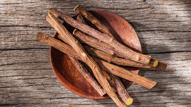 licorice root in shallow bowl on wood background