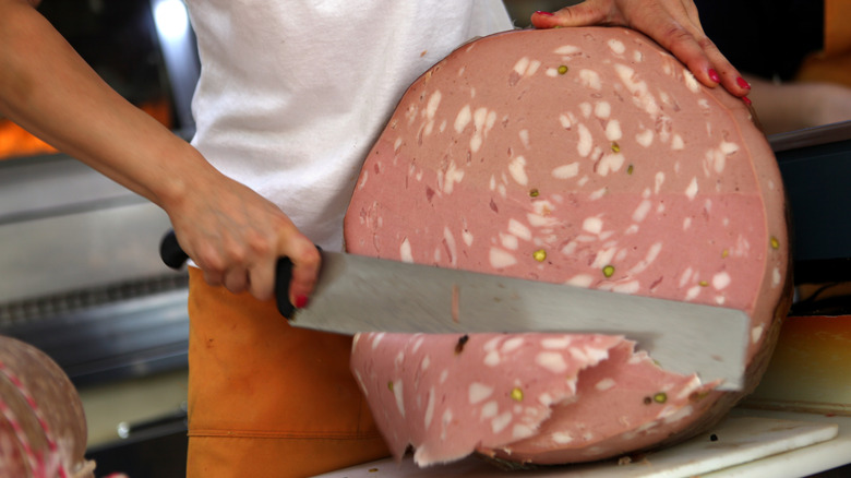 Person slicing mortadella