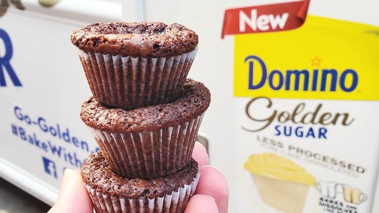 three chocolate cupcakes in front of Domino Golden Sugar sign