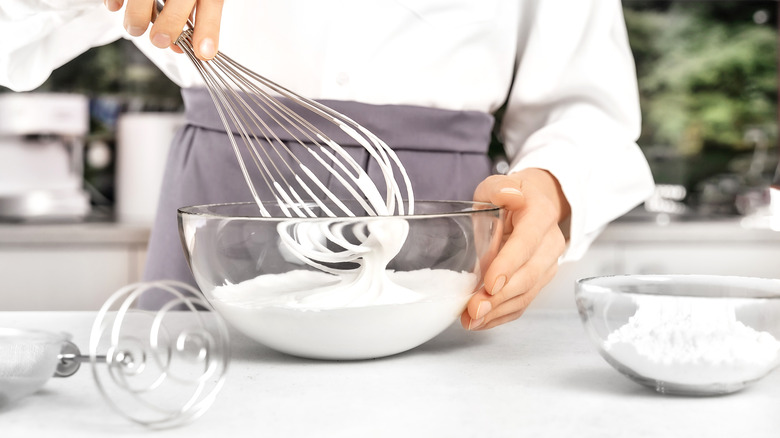 woman mixing whipped cream with a bowl of powdered sugar on the side