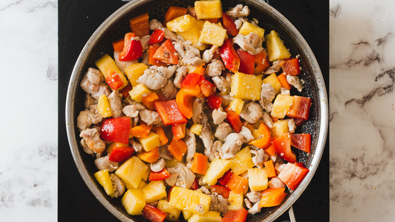 chicken, pineapple and bell peppers in pan