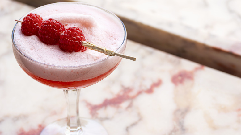 Clover Club cocktail with three raspberry garnish