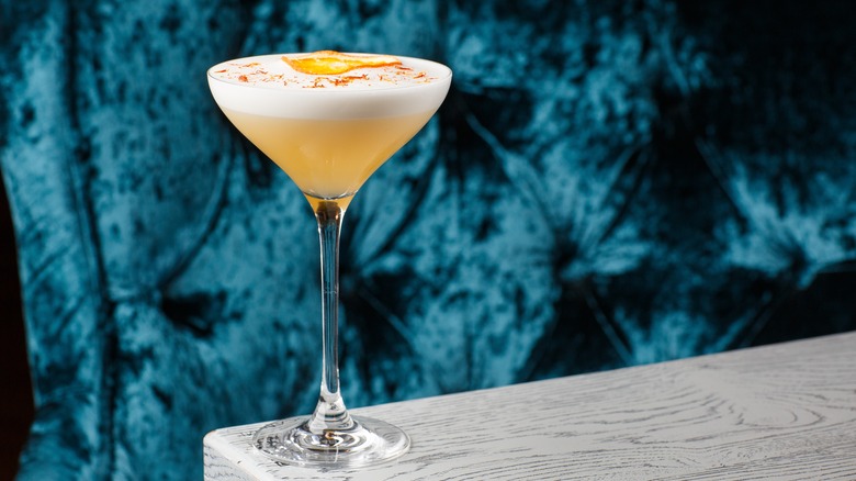 Yellow cocktail with egg white foam 