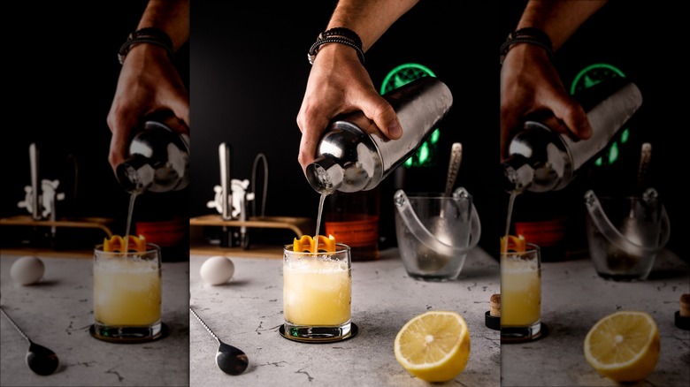 Hand pouring whiskey sour from shaker