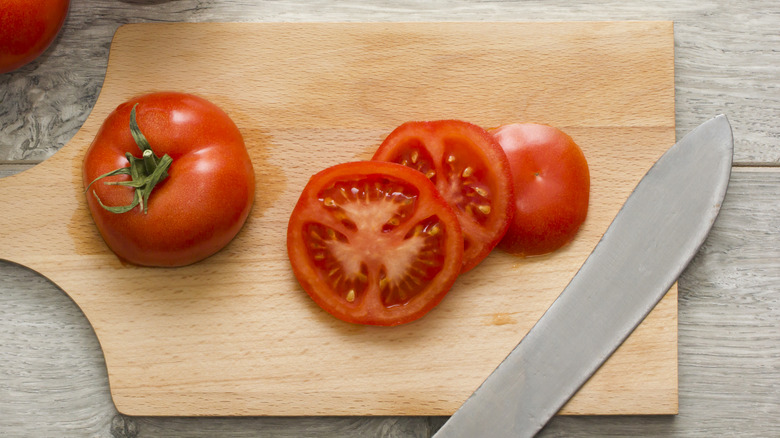 Tomatoes getting cut on board 