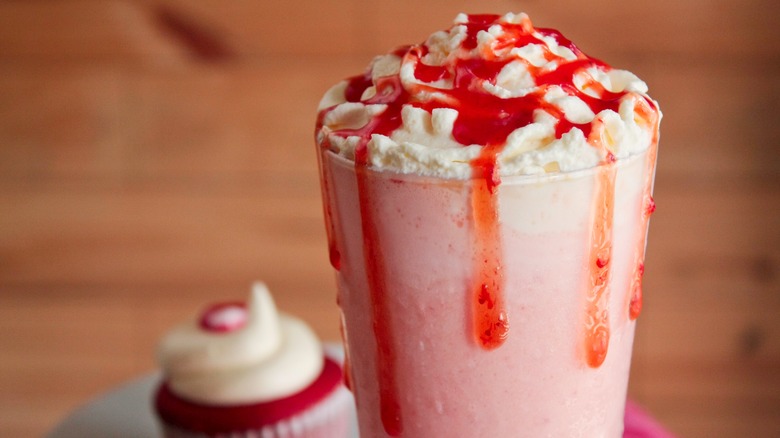 strawberry milkshake with cupcake in background