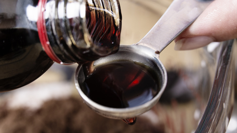 Hand pouring vanilla extract into measuring spoon