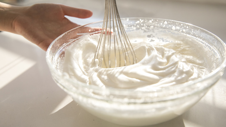 Hand holding bowl of whipped cream