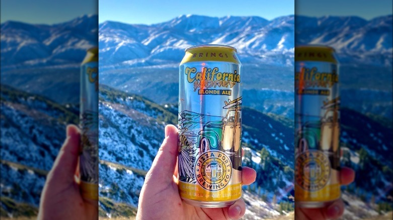 holding can of Honey Ale by mountains