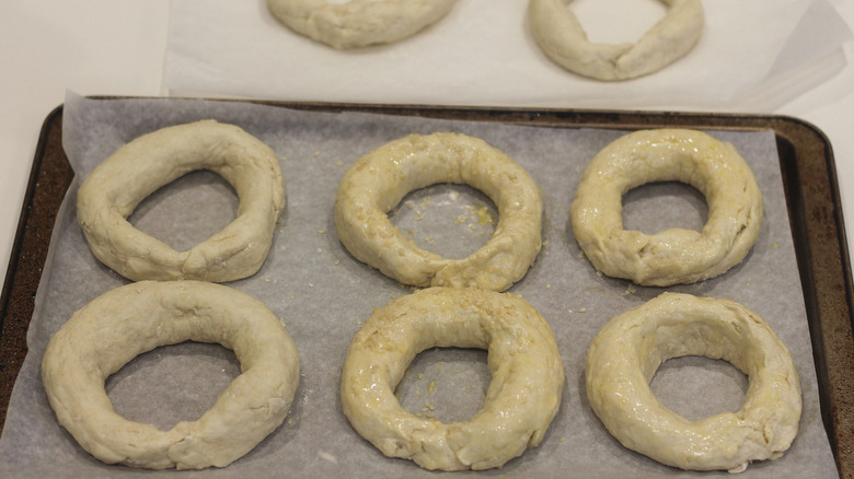 Uncooked bagels placed in a lined baking tray.