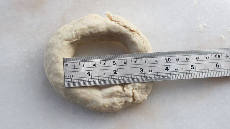 A ruler placed over an uncooked bagel.