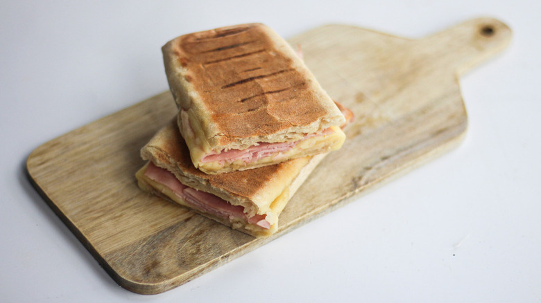 Cheese and ham panini cut on a bread board