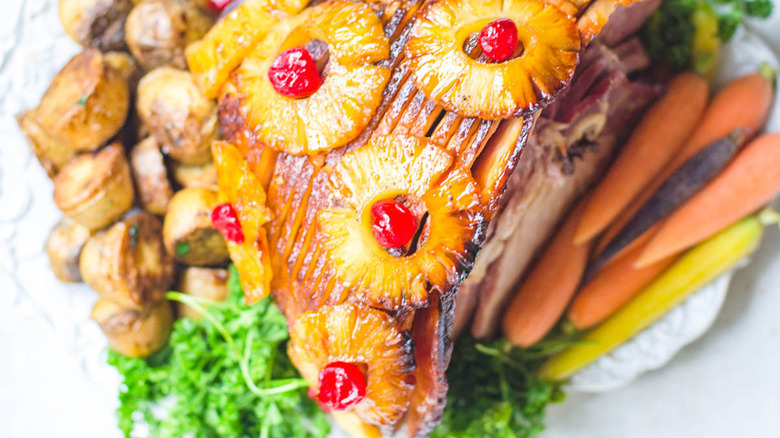 Glazed baked ham with pineapple rings and maschino cherries with veggies