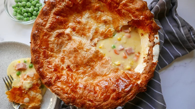 Ham pot pie with carrots and corn and a bowl of peas