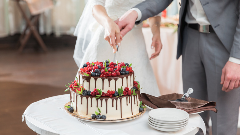 a couple's hands cutting a cake