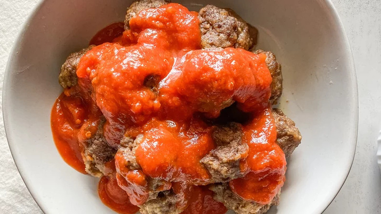 Browned meatballs with tomato sauce in a bowl.