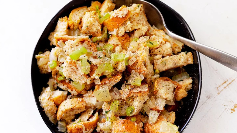 Homemade bread stuffing with celery on black plate.