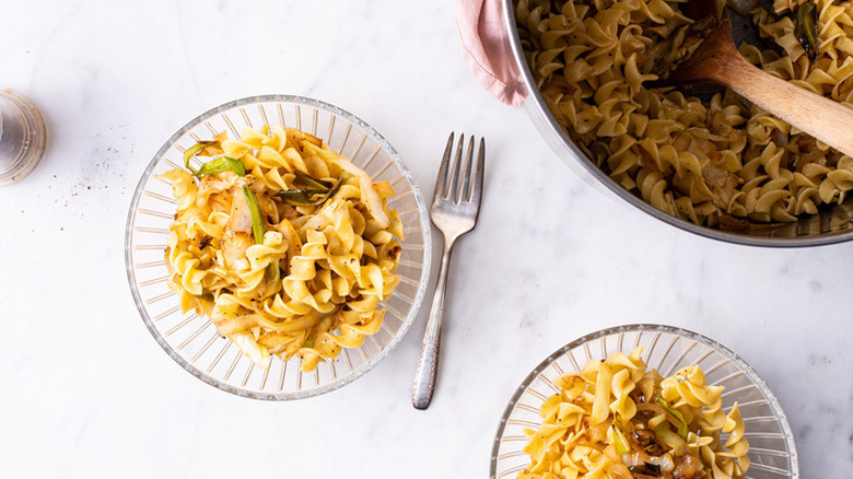 Pot and bowls full of noodles and sautéed cabbage