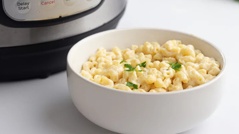 Bowl of mac and cheese next to an air fryer.