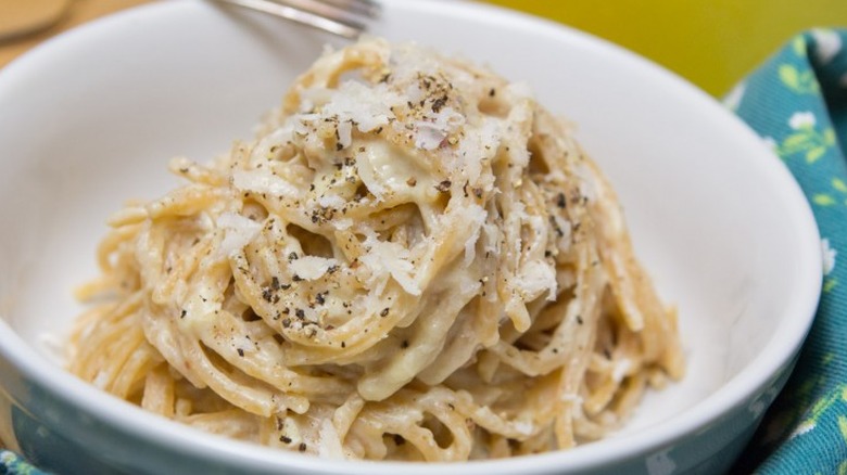 Cream sauce-coated noodles with Parmesan cheese in bowl.