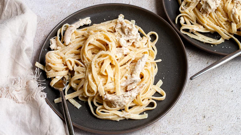 Cooked fettuccine with creamy sauce and chicken.