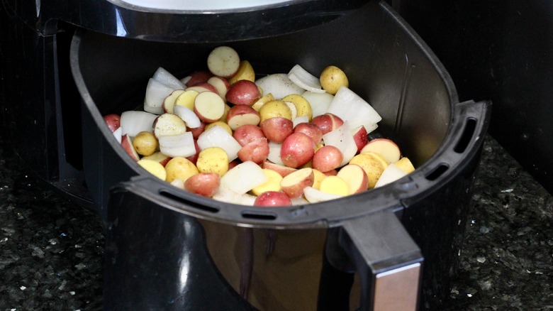 Potatoes and onions placed in air fryer basket