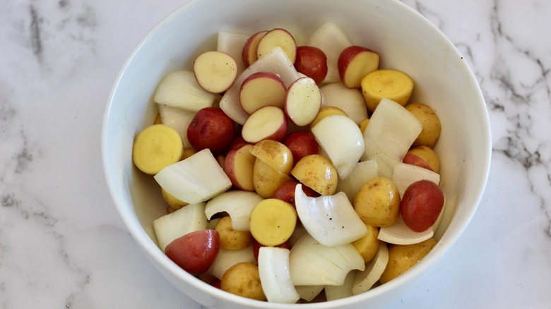 Potatoes and onions in small white mixing bowl