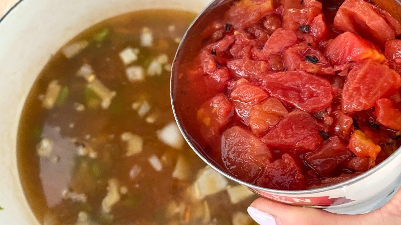 canned tomatoes poured into soup