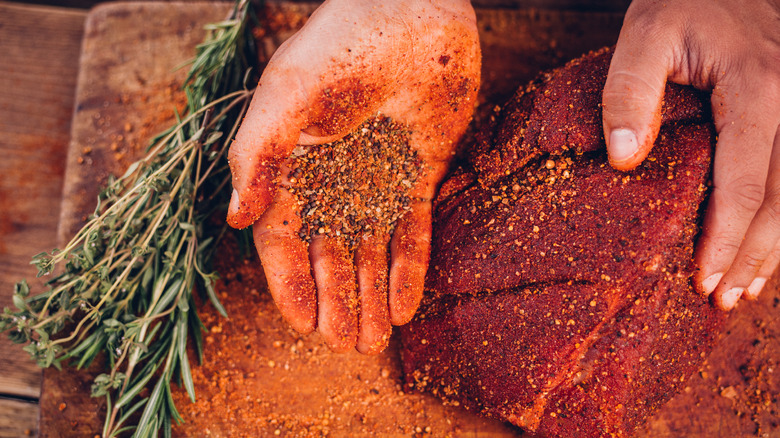 person rubbing spice onto meat