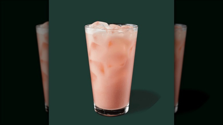 Milky peach colored drink on green background