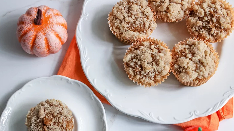 Streusel-topped pumpkin muffins on plates. 