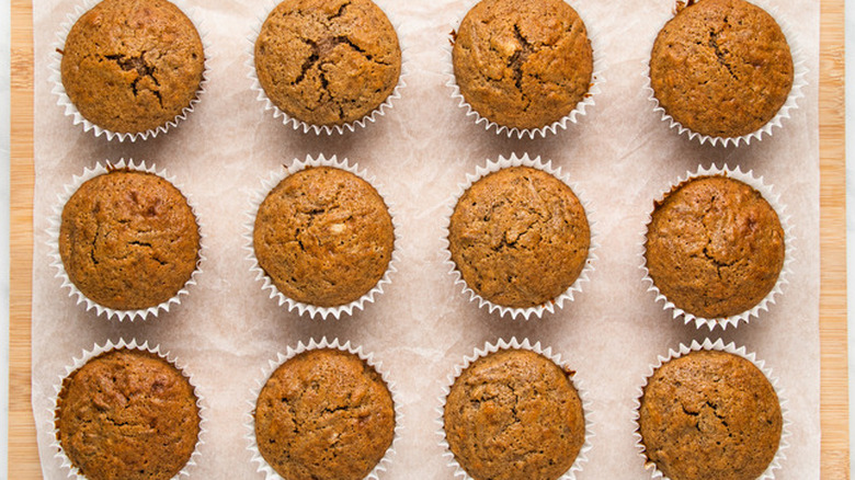 Rows of dark brown bran muffins in paper liners. 