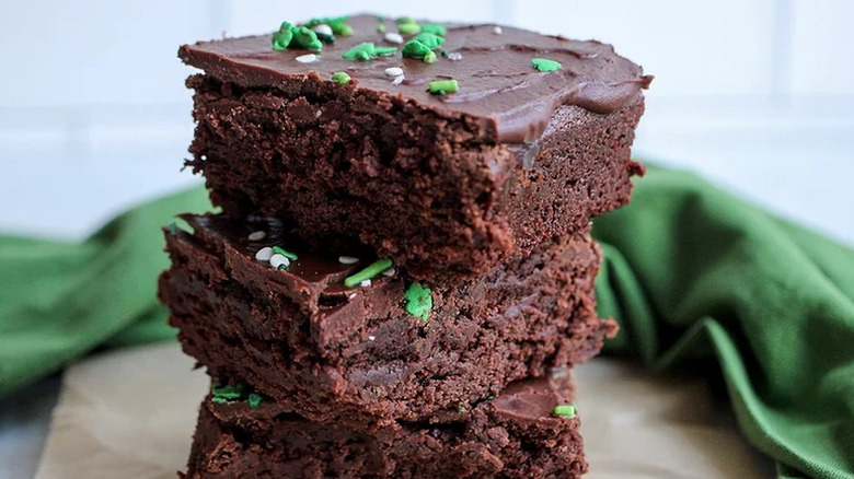 Stack of three chocolate brownies with green sprinkles.