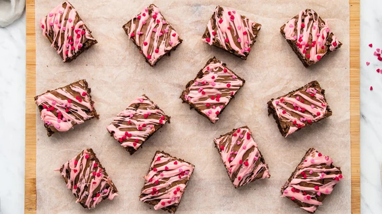 Brownies topped with pink icing and heart-shaped sprinkles.