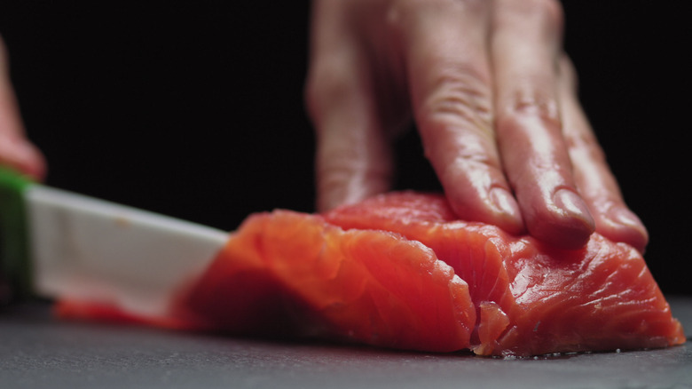 A chef's hand slicing raw fish