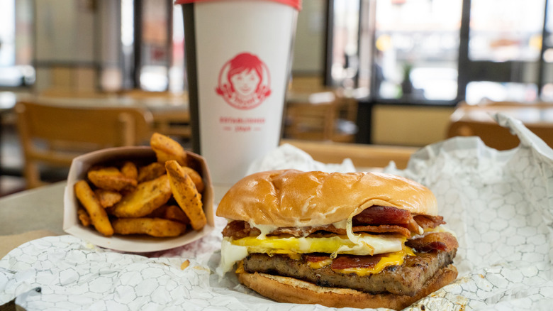 Wendy's breakfast baconator next to potatoes and drink